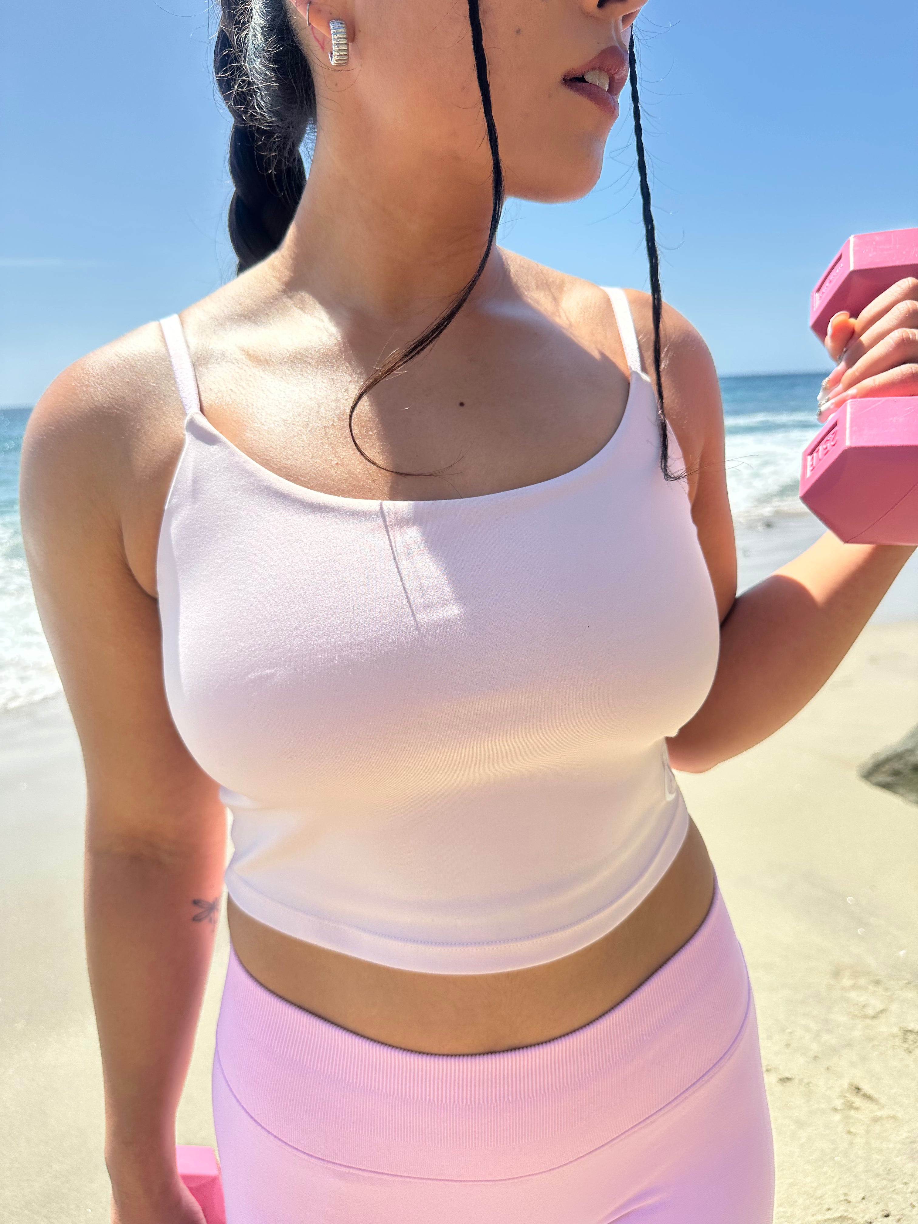 Woman exercising on a beach with pink dumbbells